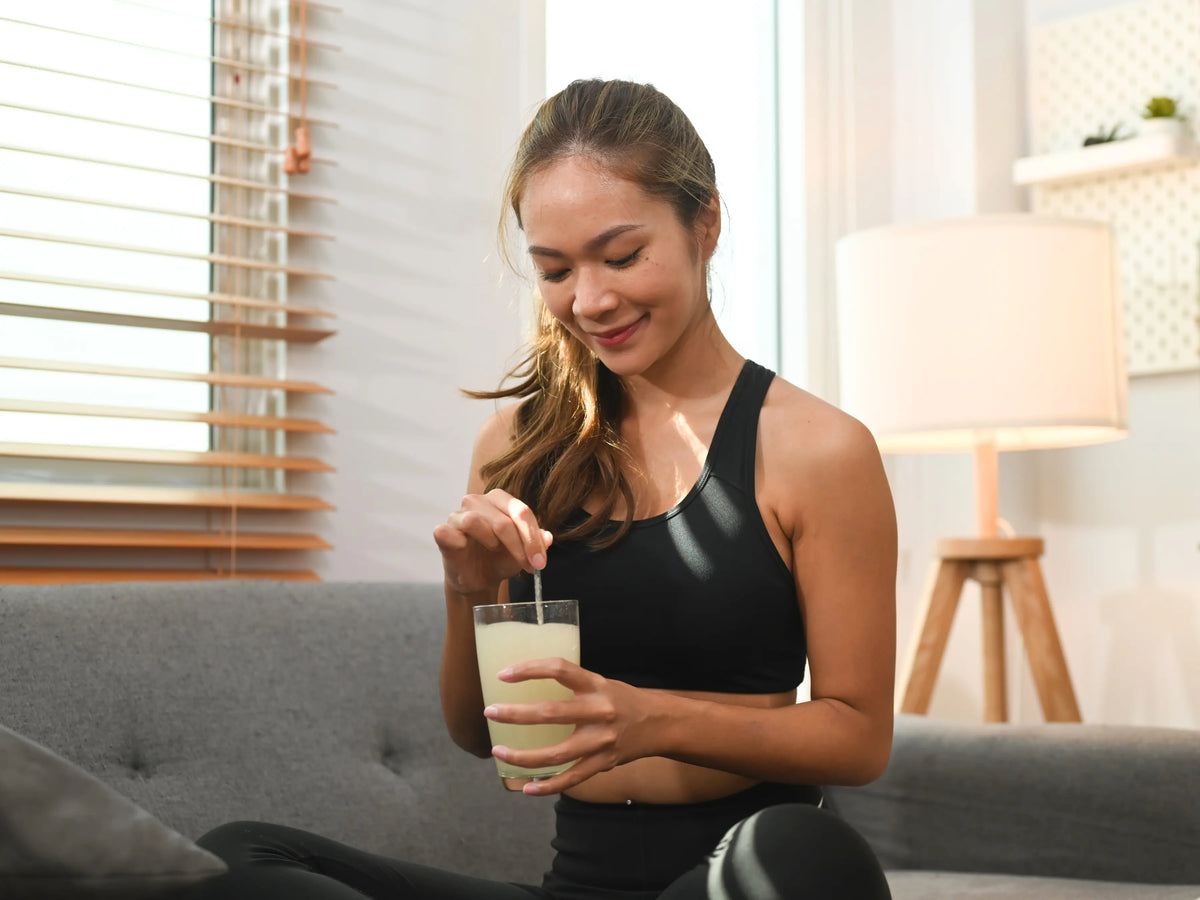 Femme en tenue de sport qui remue une boisson dans un verre avec une cuillère